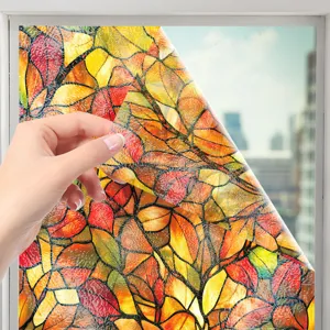 Gros plan de film de vitrail coloré avec motif de feuilles d'automne appliqué sur la fenêtre.