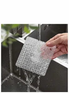 Close-up detail of flexible silicone cleaning pad rinsing under kitchen water tap.