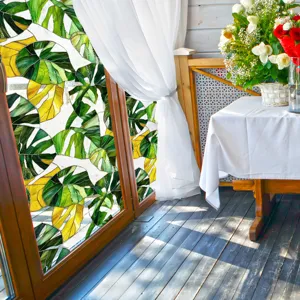 Gros plan détaillé du film pour fenêtre décoratif avec motif de feuilles tropicales sur vitre.