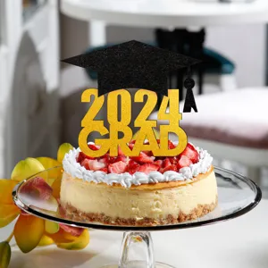 Closeup view of graduation cake topper with gold glitter 2024 grad text and black cap.