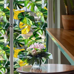 Détail de film pour vitre avec motif coloré de feuilles tropicales monstera vert et jaune.