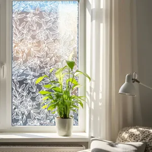 Lace window film detail showing white floral pattern on glass in bright living room.