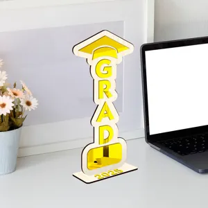Vista detallada de adorno de mesa de graduación de madera con GRAD y 2025 en escritorio blanco.