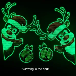 Dettaglio ravvicinato di adesivi natalizi luminosi con renne e campane effetto notte.