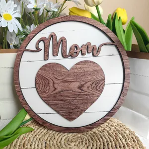 Close-up detail of wooden Mother's Day sign with heart puzzle and Mom cutout decor.