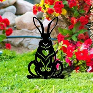 Gros plan d'un piquet de jardin silhouette de lapin noir avec découpe en cœur dans l'herbe.