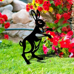 Gros plan détaillé d'un piquet de jardin noir en forme de lapin sur de l'herbe verte.