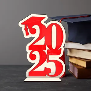Vista detallada de la decoración de mesa de madera de graduación 2025 con libros apilados.