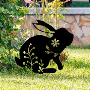 Vue détaillée du piquet de jardin lapin noir avec motif floral creux sur pelouse verte.