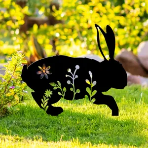 Gros plan sur le piquet de jardin lapin noir avec découpes florales sur fond de pelouse.