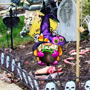 Detalle de estaca de jardin de gnomo bruja de Halloween con decoracion de cementerio y caldero.