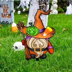 Vista de cerca de estaca de jardín de Halloween con sombrero de bruja y calabaza en césped.