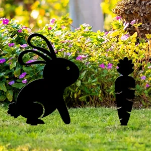 Détail de la scène de jardin extérieur montrant les piquets décoratifs noirs de lapin et carotte