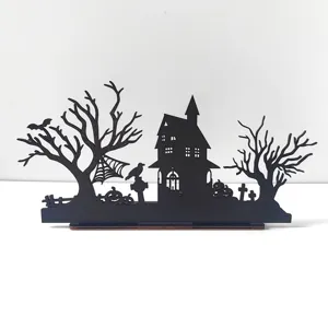 Halloween wooden table decor detail showing intricate haunted house and tree silhouettes.