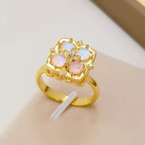 Elegante anello geometrico dorato con quattro pietre opalescenti e dettagli di cristalli.