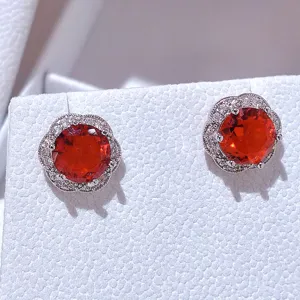 Primo piano dettagliato di orecchini a lobo floreali di lusso con pietra rossa e zirconi.