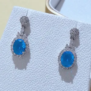 Splendidi orecchini pendenti con pietra ovale blu e pavé di zirconi brillanti in primo piano.