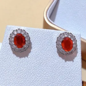 Dettaglio ravvicinato di orecchini di lusso ovali in cristallo rosso con zirconi cubici.