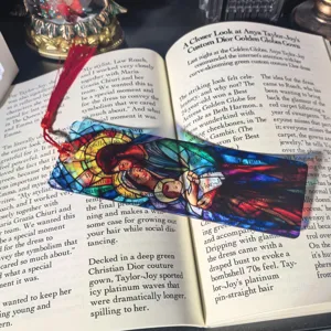 Transparent acrylic bookmark with colorful stained glass religious art and red tassel.
