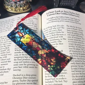 Transparent acrylic bookmark with candle stained glass design and red tassel for reading.