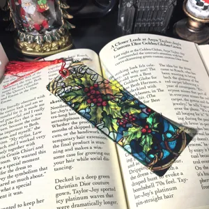 Transparent acrylic Christmas holly bookmark with red tassel showcased on open book detail