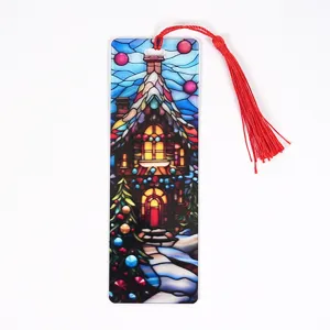 Close-up detail of a Christmas acrylic bookmark with red tassel, stained glass style house.