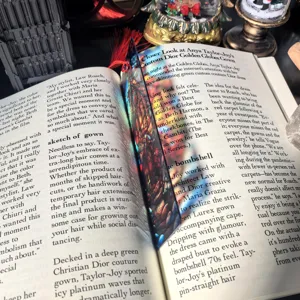 Detail view of transparent acrylic bookmark with vibrant colorful art print and red tassel.