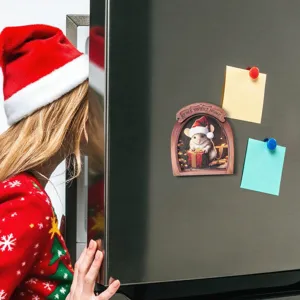 Close-up view of a 3D wooden mouse hole Christmas fridge magnet on a stainless steel refrigerator.