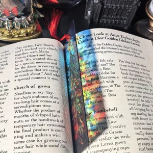 Detail shot of a transparent acrylic bookmark with colorful stained glass design and red tassel.