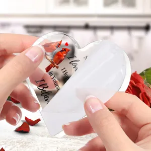 Hartvormig acryl ornament detail toont beschermfolie afpelproces met rode kardinaal.