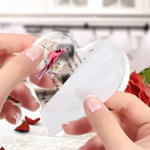 Gedetailleerd shot van een doorzichtig acryl hart ornament met rode kardinaalvogel en tekst.