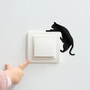 Detailed shot of a stylish black acrylic cat wall sticker placed next to a white light switch.