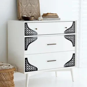 Vista dettagliata di adesivi angolari in acrilico nero con design geometrico su mobile bianco.
