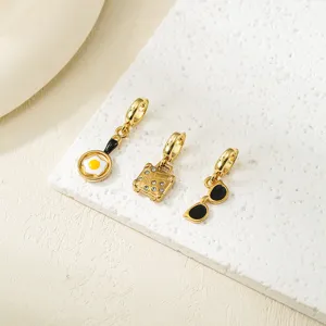 Gros plan de charms pendentifs DIY en acier inoxydable doré avec des formes amusantes d'œufs.