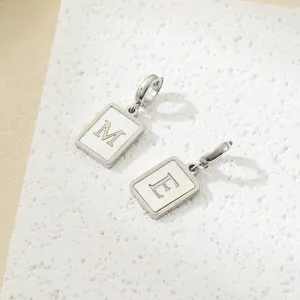 Dettaglio pendente quadrato con conchiglia e lettere M ed E, accessorio per gioielli fai da te.