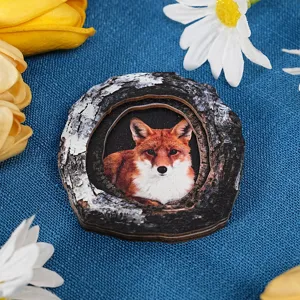 Close up detail of wooden tree trunk fox magnetic sticker, home decor craft on blue fabric.