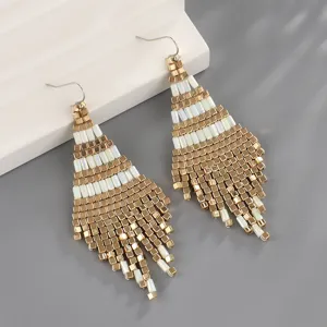Κοντινό πλάνο σε boho χρυσά και λευκά σκουλαρίκια με χάντρες, χειροποίητο σχέδιο.