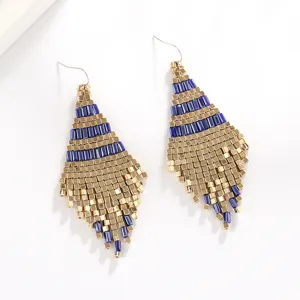 Λεπτομερές κοντινό πλάνο από χειροποίητα boho σκουλαρίκια με χάντρες σε μπλε και χρυσούς τόνους.