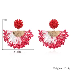 Handcrafted beaded tassel earrings featuring red and white rice beads with gold tone metal.
