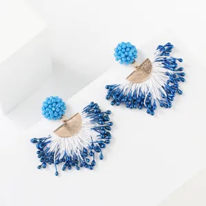 Detailed close-up shot of blue and white beaded tassel earrings with gold metal elements.
