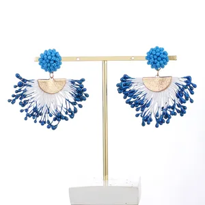 Detailed view of handmade blue and white beaded tassel earrings featuring golden semi-circle accents.