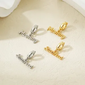 Close-up detail shot of metal letter pendants featuring Mammy and Sisterhood words in gold and silver.