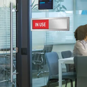 Office door sign detail view showing sliding red indicator for meeting room privacy management.