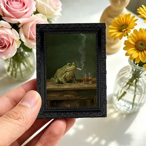 Miniature vintage photo frame fridge magnet detail showing humorous frog painting and textured black edge.