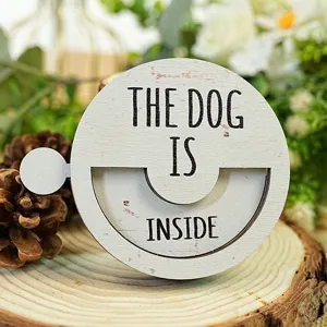 Close-up detail of a round wooden pet status sign featuring engraved text and natural wood texture.