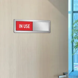 Office door status slider sign detail view showing red IN USE indicator on brushed metal frame.