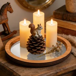 Plateau à bougies miroir en bois avec écureuil décoratif pomme de pin et bougies vue de détail.