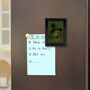 Close-up detail shot of the vintage frog picture frame fridge magnet on refrigerator door.