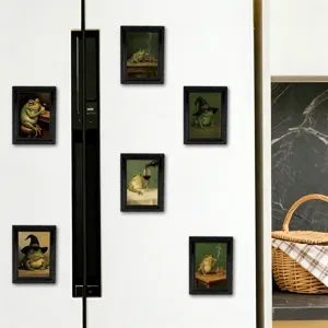 Detail shot of vintage style frog refrigerator magnets in black frames displayed on white fridge.
