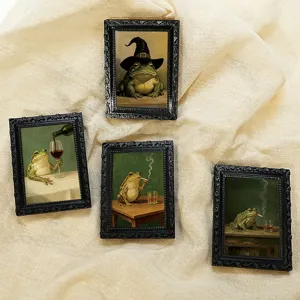 Close-up detail of vintage miniature black photo frame fridge magnets featuring quirky frog art.